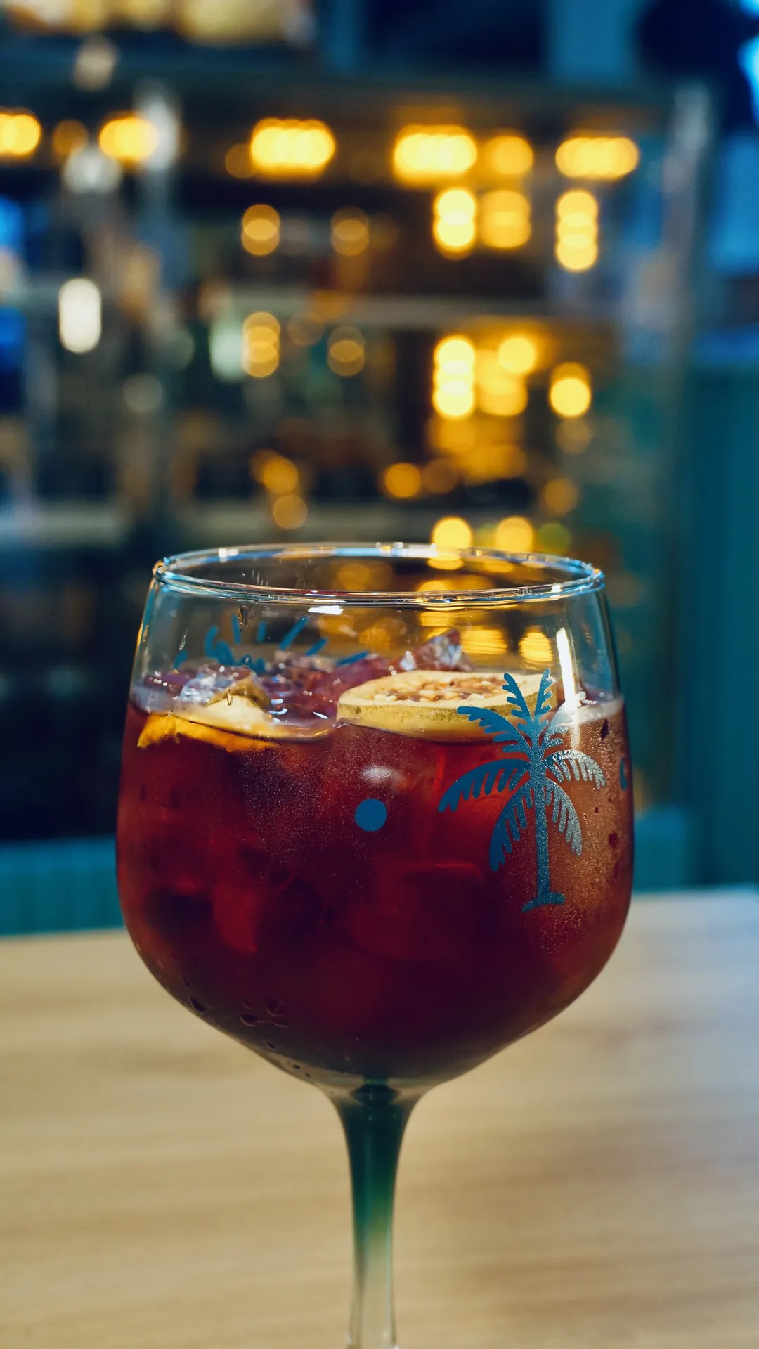 Copa de sangría con frutas sobre la barra, luces de fondo