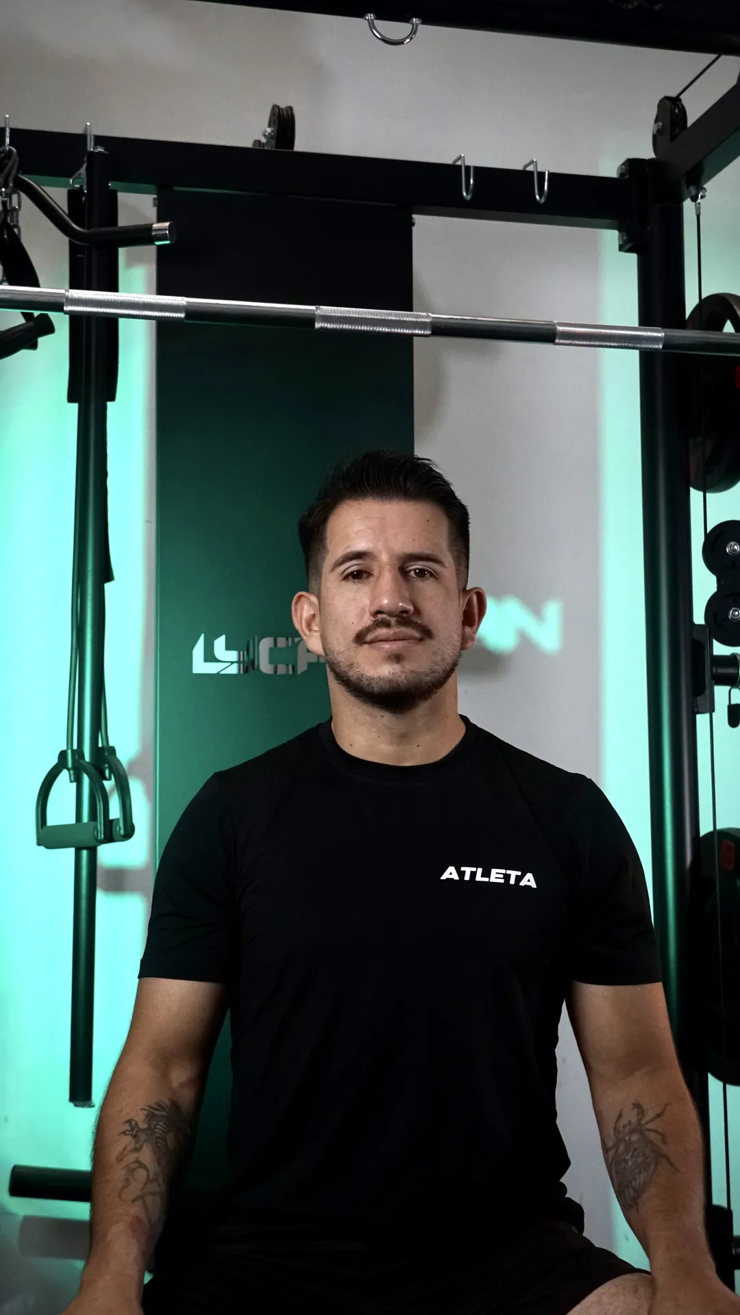 Entrenador con camiseta negra en el gimnasio, luz verde de fondo