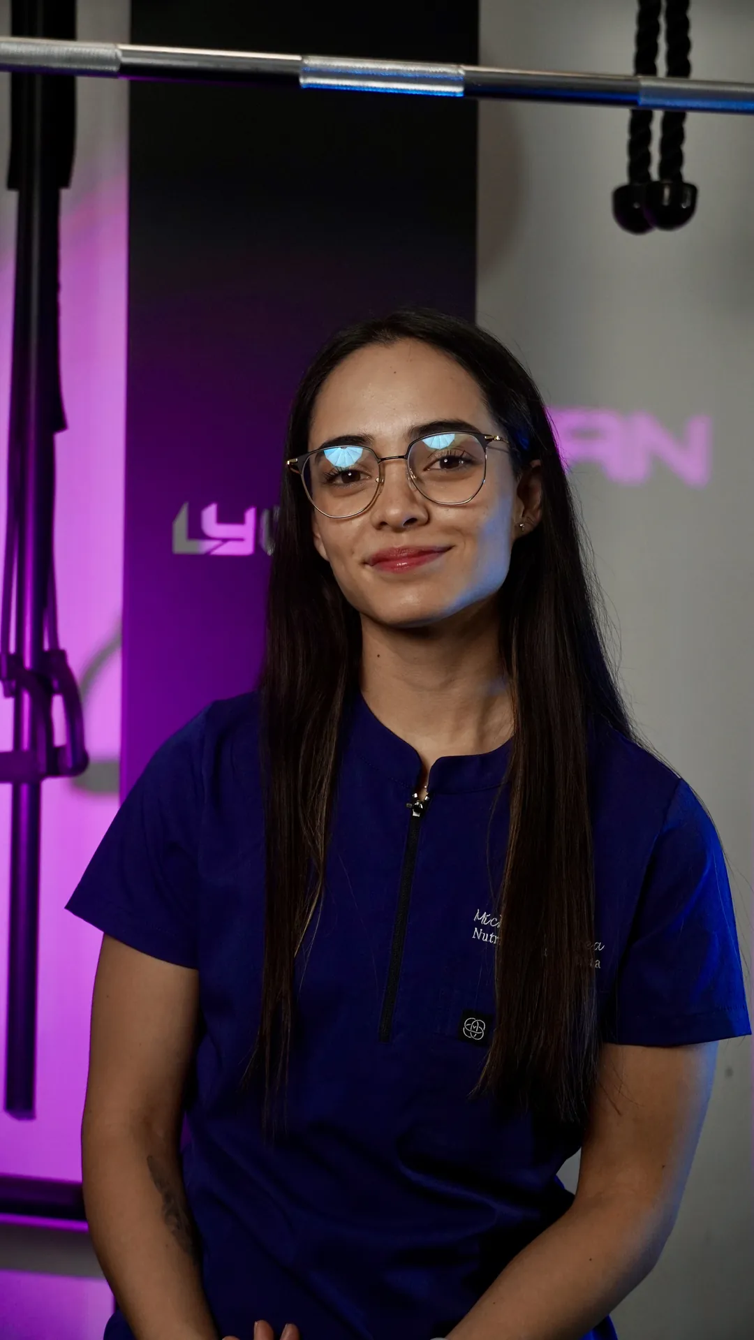 Mujer con lentes y uniforme azul, luz morada de fondo